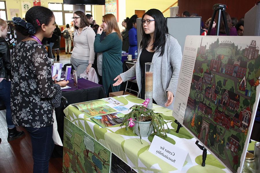 Students talk to staff member standing behind a table